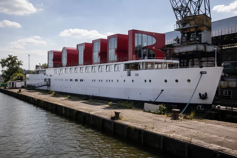 Floating hotel ship with quirky rooftop rooms moored at an industrial Amsterdam shipyard