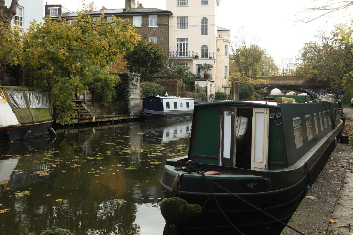 A converted luxury narrowboat moored along a scenic English canal