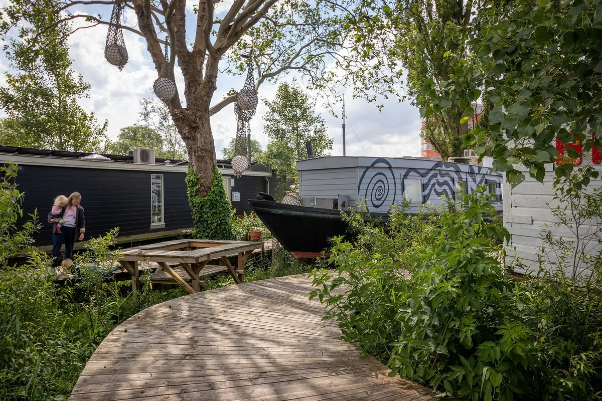 Hotel Asile Flottant’s vintage Dutch houseboats moored along a leafy Amsterdam canal