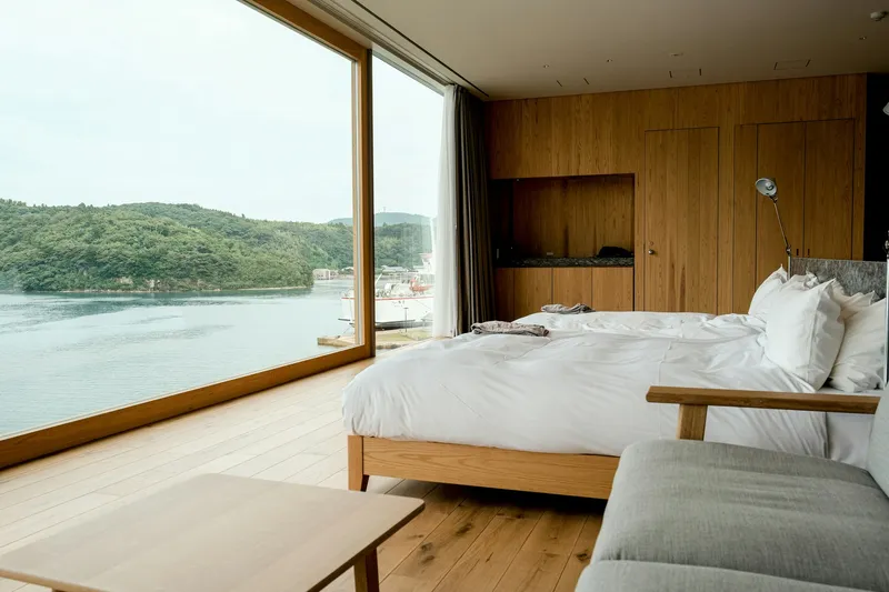Floating hotel cabin bedroom with a panoramic window overlooking the water