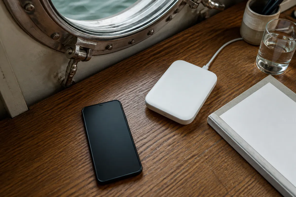 Compact travel router and smartphone on a desk inside a ship cabin