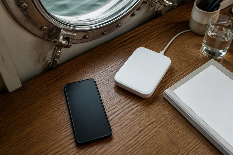 Compact travel router and smartphone on a desk inside a ship cabin